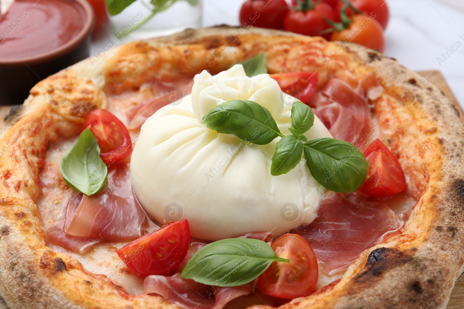 Photo of Delicious pizza with burrata cheese, basil, tomatoes and ham on table, closeup