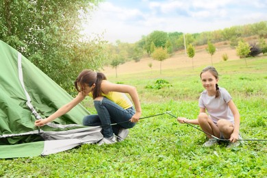 Photo of Mother and her daughter setting up camping tent outdoors