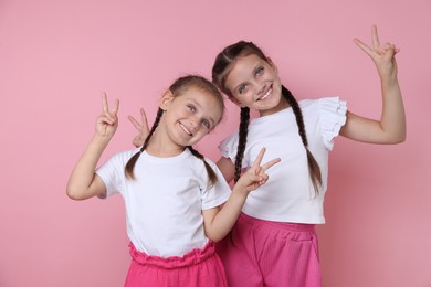 Portrait of cute little sisters on pink background