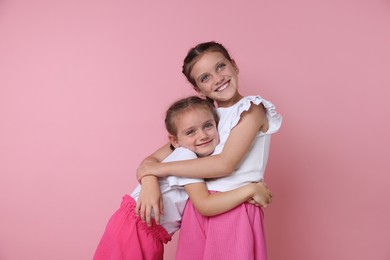 Photo of Portrait of cute little sisters on pink background