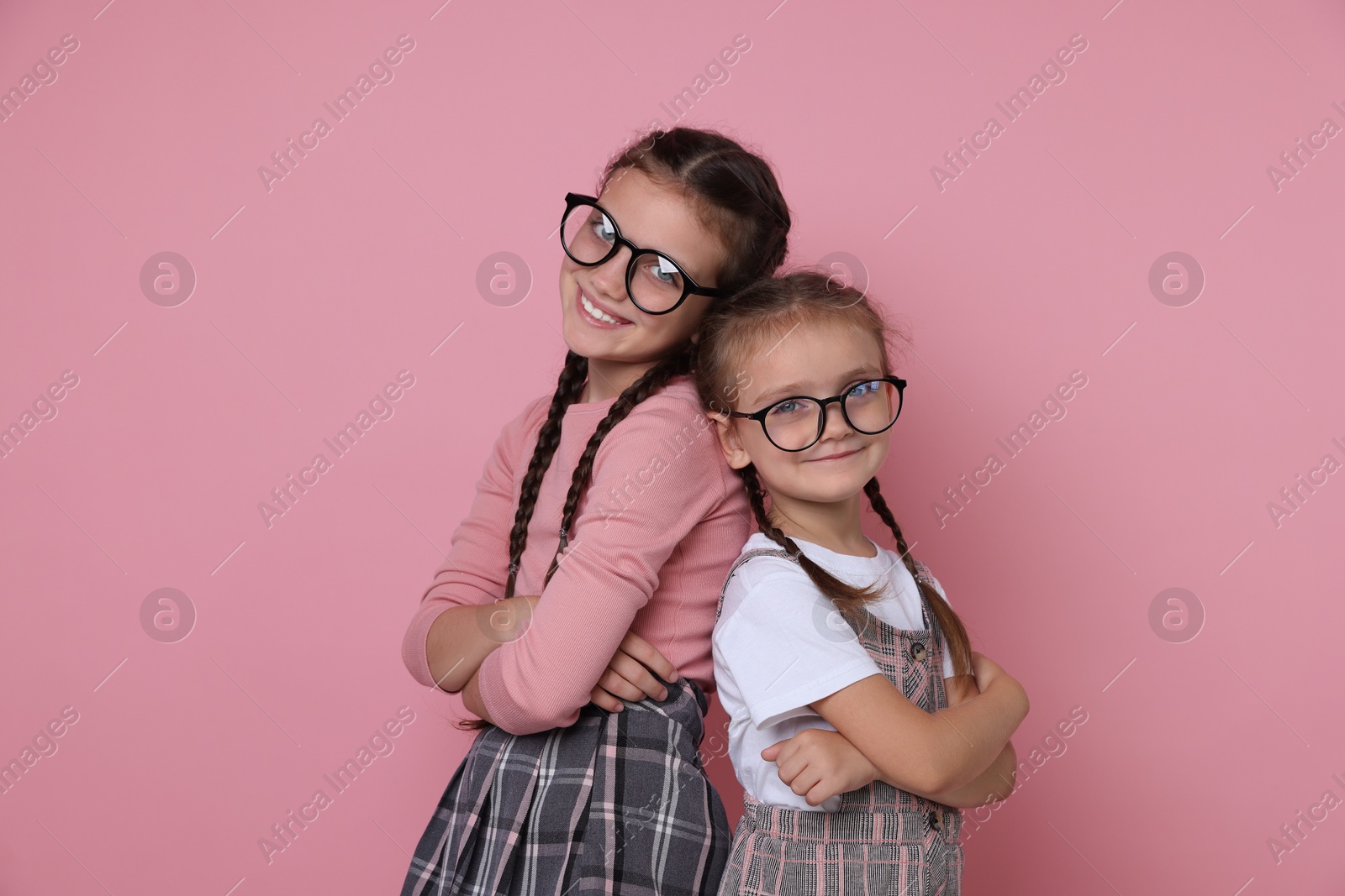 Photo of Portrait of cute little sisters on pink background