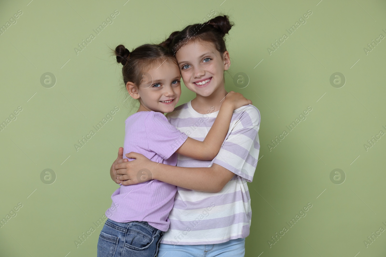 Photo of Portrait of cute little sisters on light green background