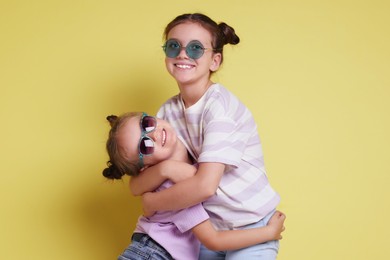 Portrait of cute little sisters on yellow background