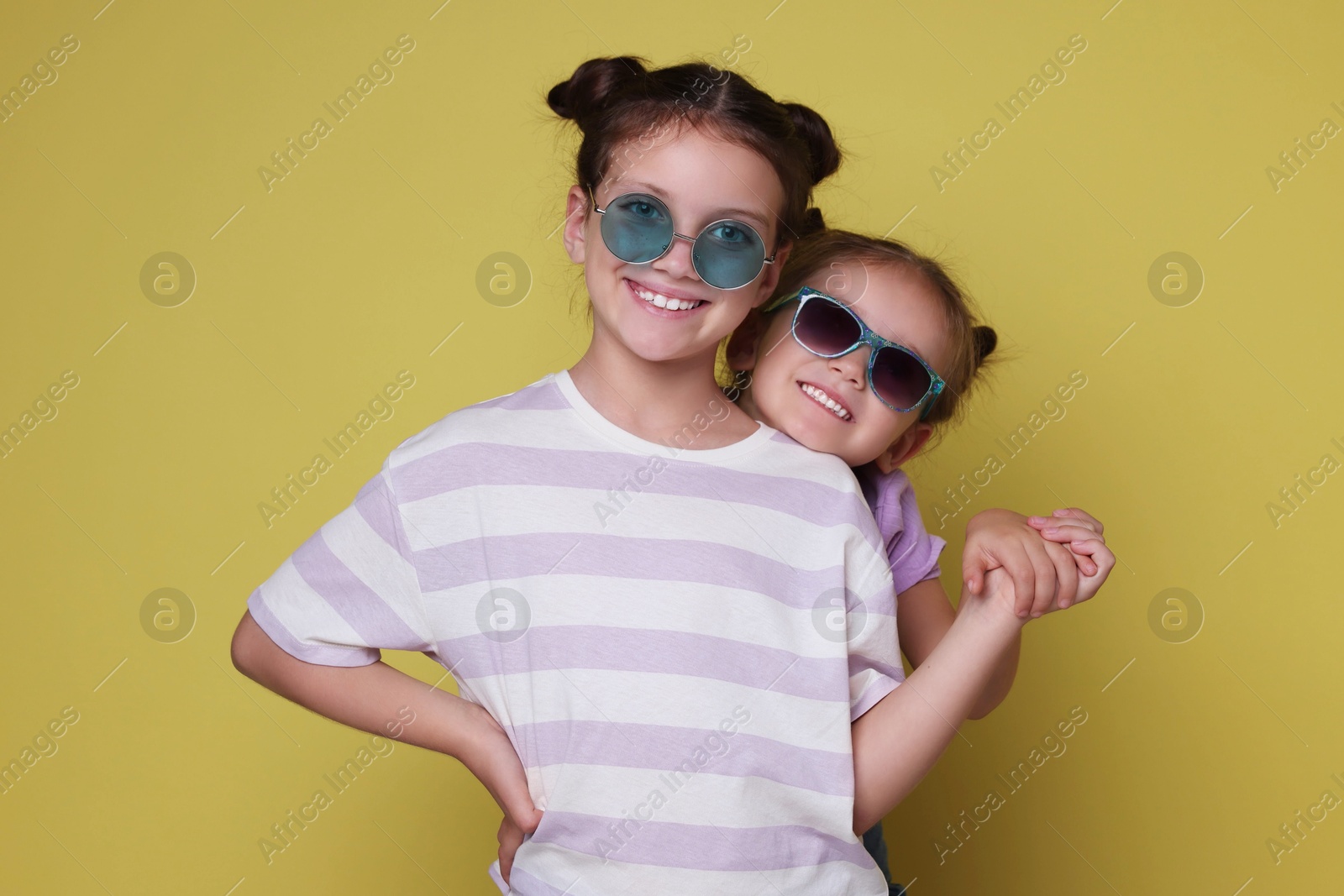 Photo of Portrait of cute little sisters on yellow background