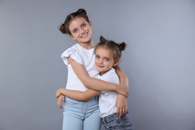 Photo of Portrait of cute little sisters on grey background