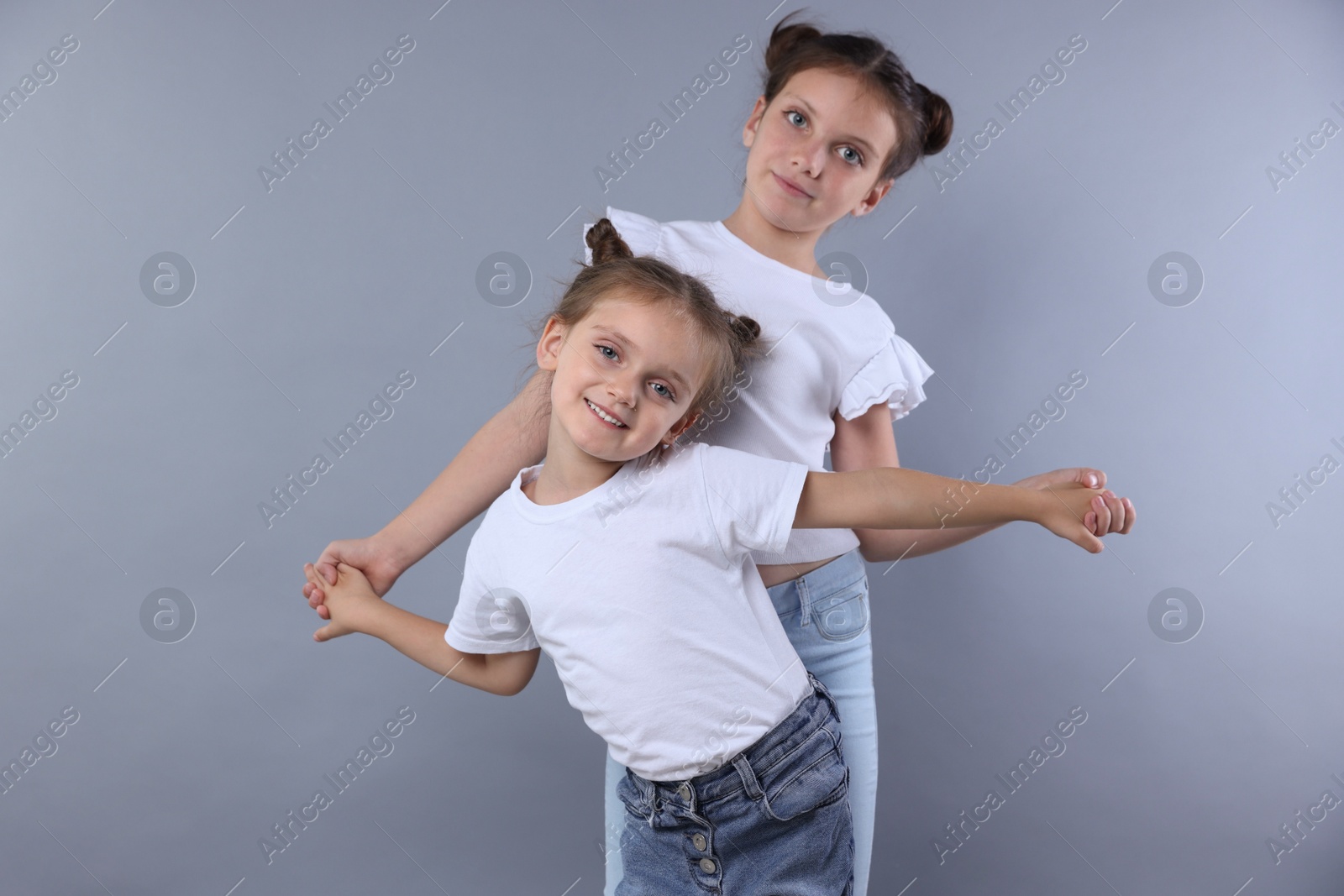 Photo of Portrait of cute little sisters on grey background