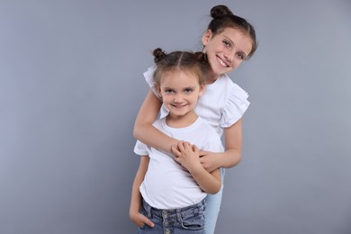 Portrait of cute little sisters on grey background