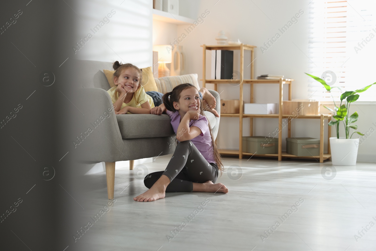 Photo of Cute little sisters spending time together at home, space for text