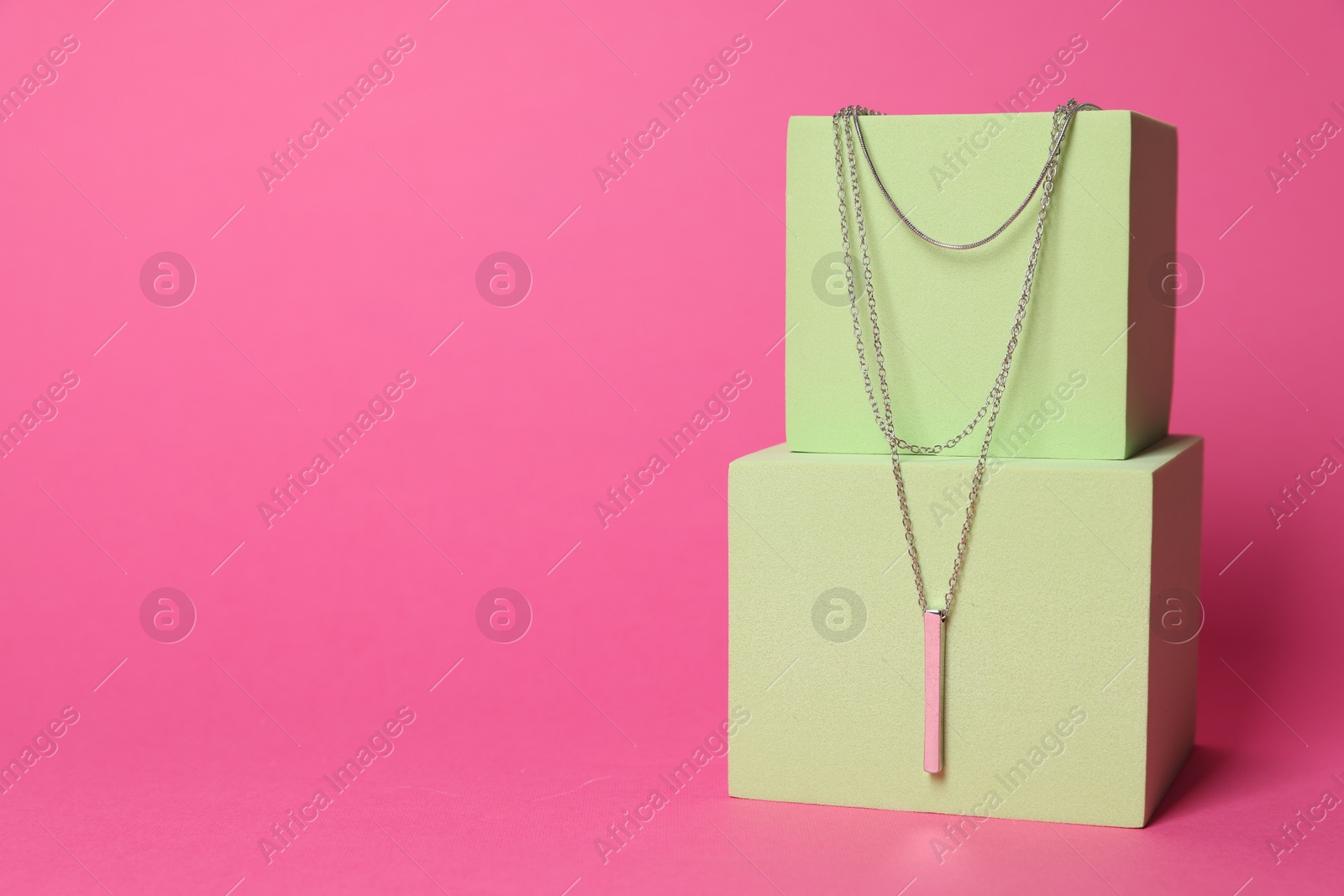 Photo of Stylish presentation of beautiful necklace on pink background. Space for text