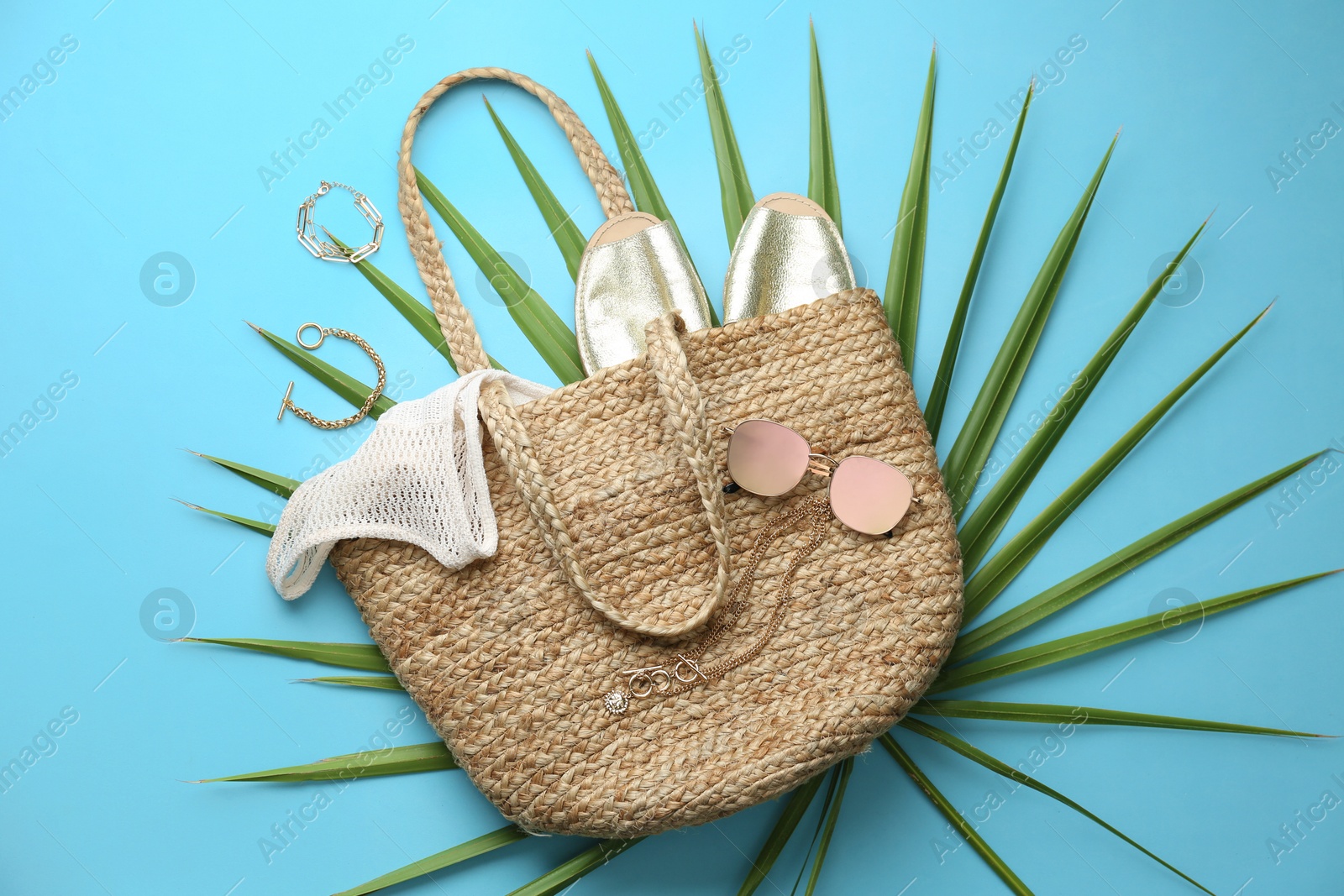 Photo of Flat lay composition with woman's straw bag on light blue background