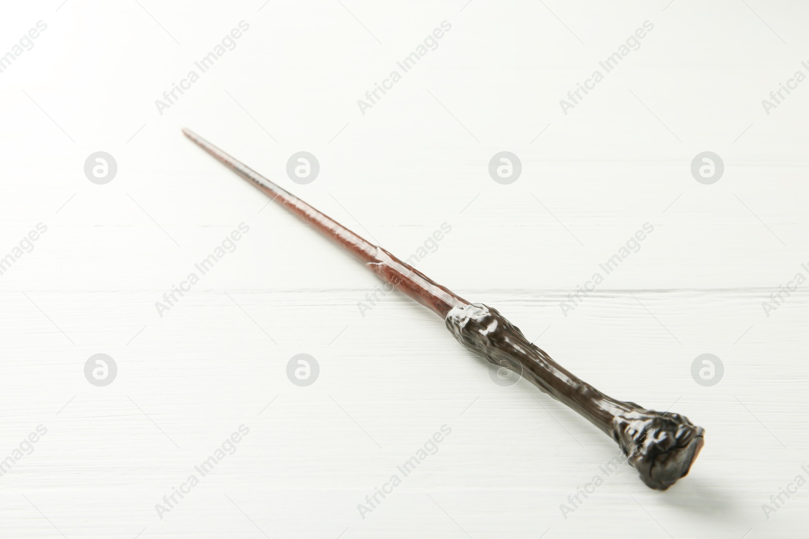 Photo of One old magic wand on white wooden table, closeup