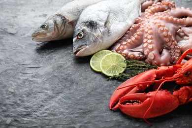 Photo of Sea food. Fresh raw octopus, fish and lobster on black table, closeup. Space for text