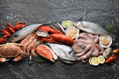 Fresh fish and different sea food on black table, top view