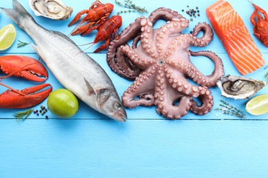 Different sea food on light blue wooden table, flat lay. Space for text