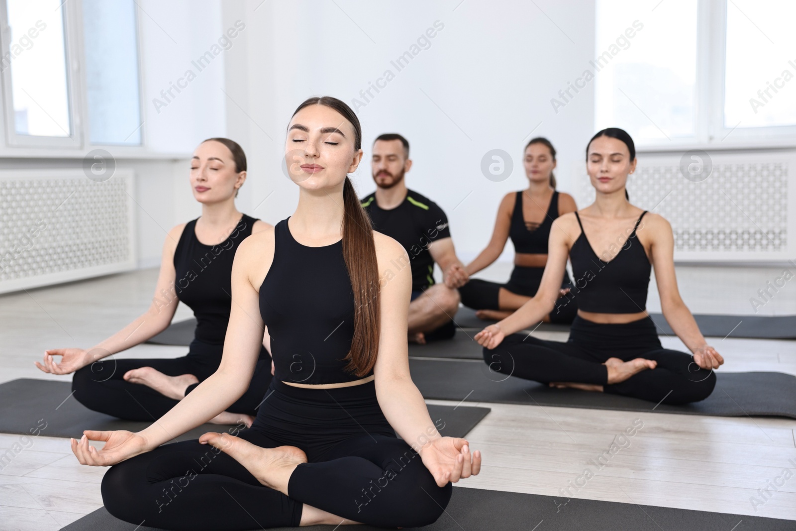 Photo of Group of people meditating on mats in yoga class