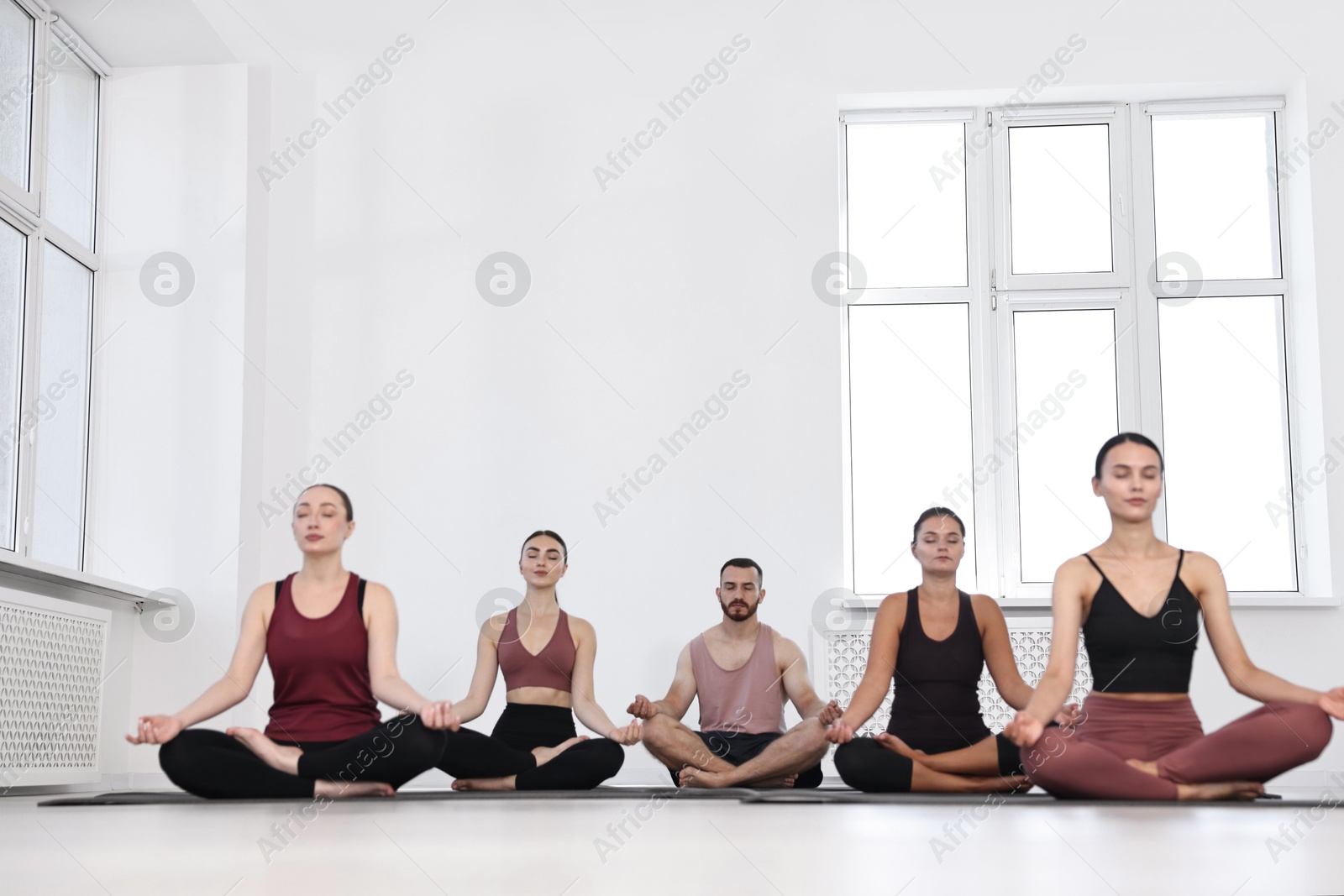 Photo of Group of people meditating on mats in yoga class