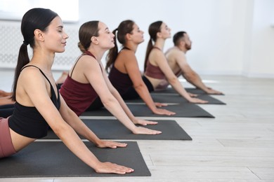 Photo of Group of people practicing yoga on mats in class. Space for text