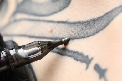 Woman making tattoo with machine, macro view