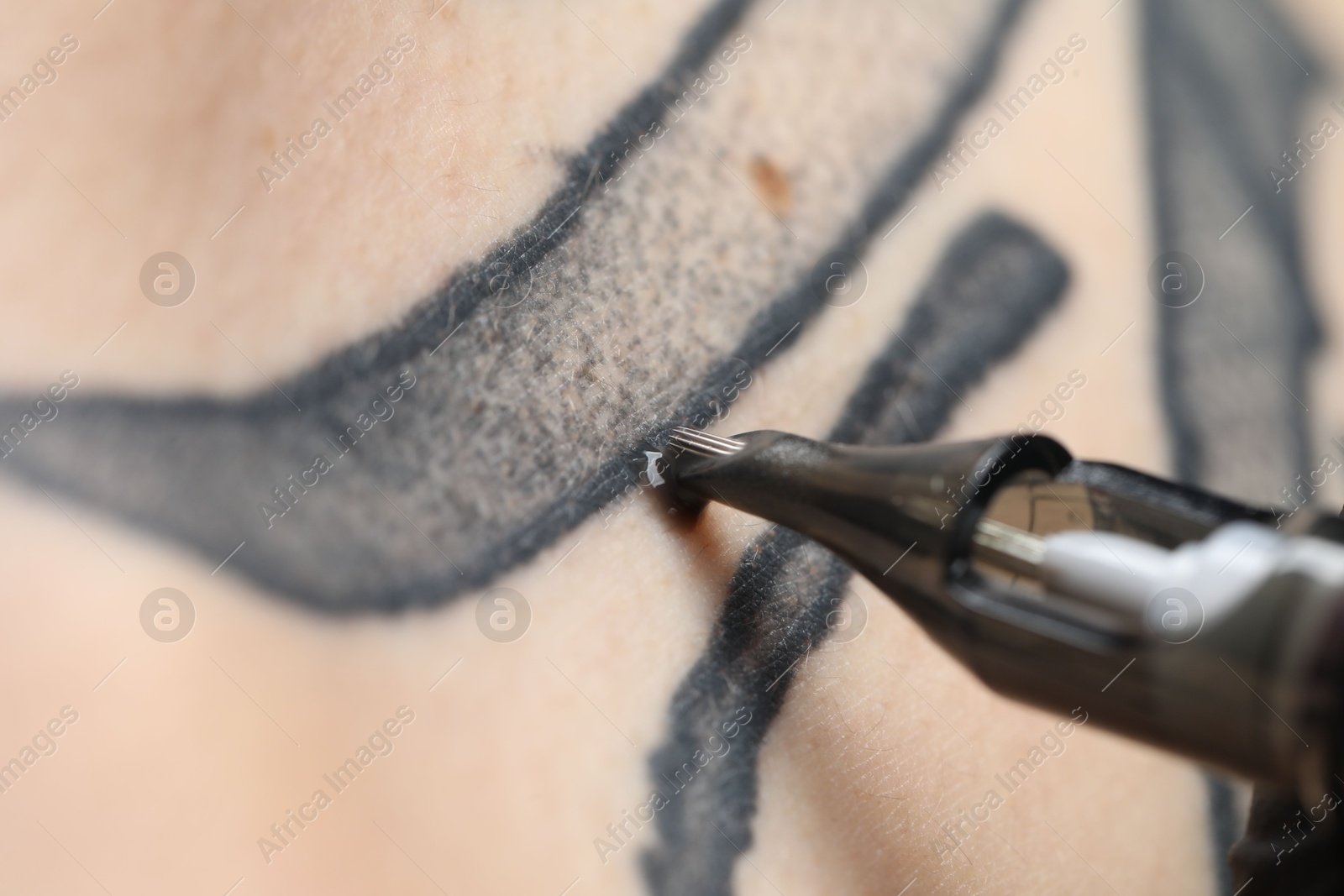 Photo of Woman making tattoo with machine, macro view