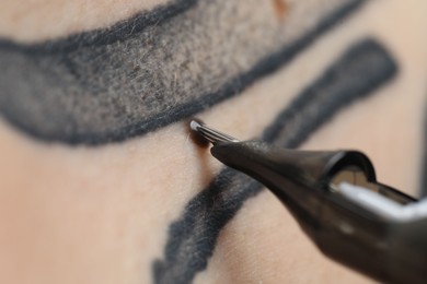 Woman making tattoo with machine, macro view