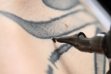 Photo of Woman making tattoo with machine, macro view