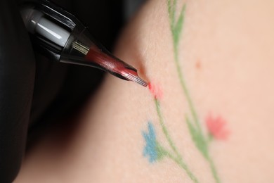 Photo of Woman making tattoo with machine, macro view