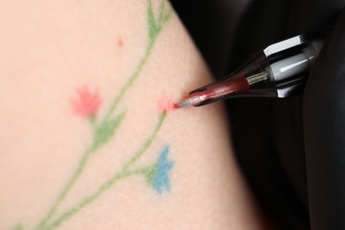 Photo of Woman making tattoo with machine, macro view