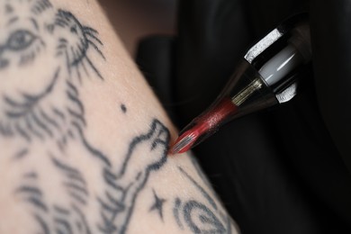 Photo of Artist in glove tattooing woman with machine, macro view