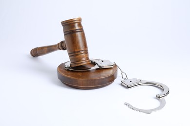 Photo of Handcuffs and judge's gavel isolated on white