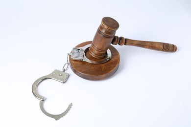 Photo of Handcuffs and judge's gavel isolated on white