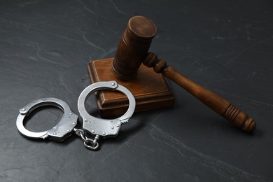 Photo of Handcuffs and judge's gavel on grey textured table