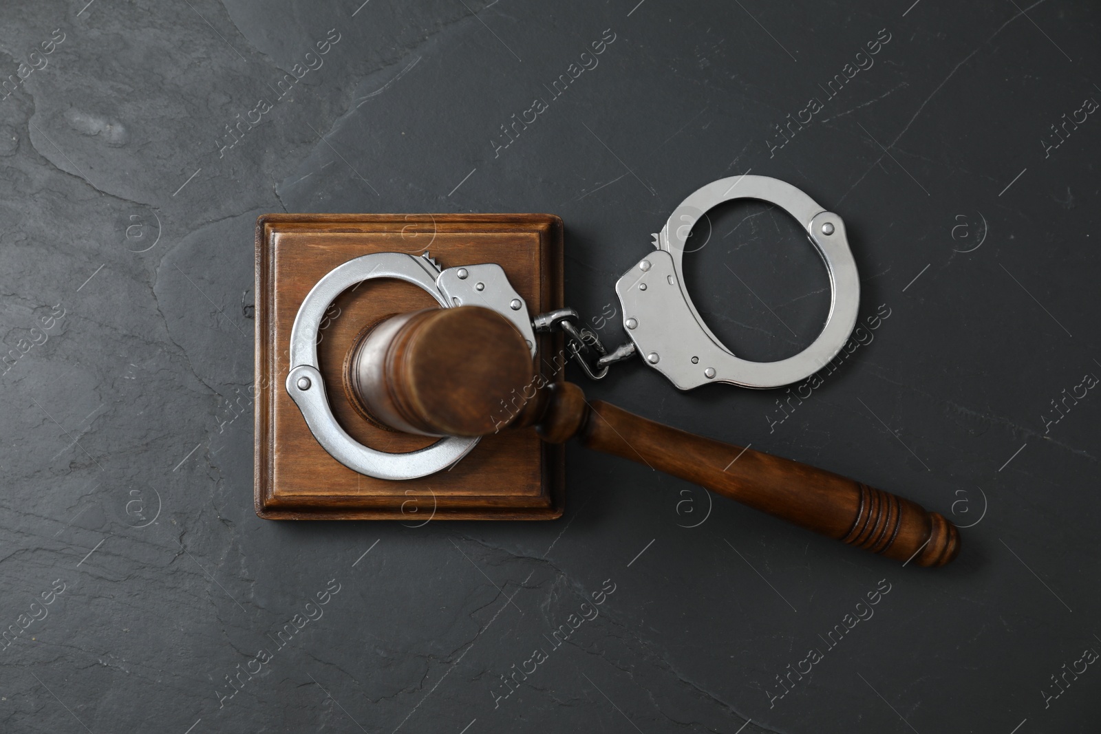 Photo of Handcuffs and judge's gavel on grey textured table, flat lay