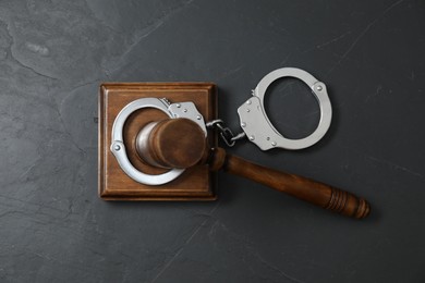 Handcuffs and judge's gavel on grey textured table, flat lay