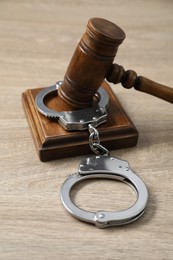 Handcuffs and judge's gavel on wooden table