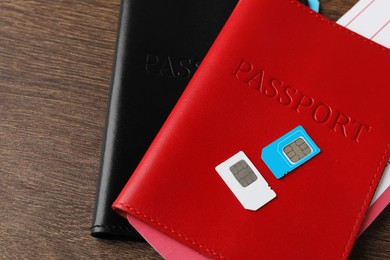 Passports and SIM cards on wooden table, closeup