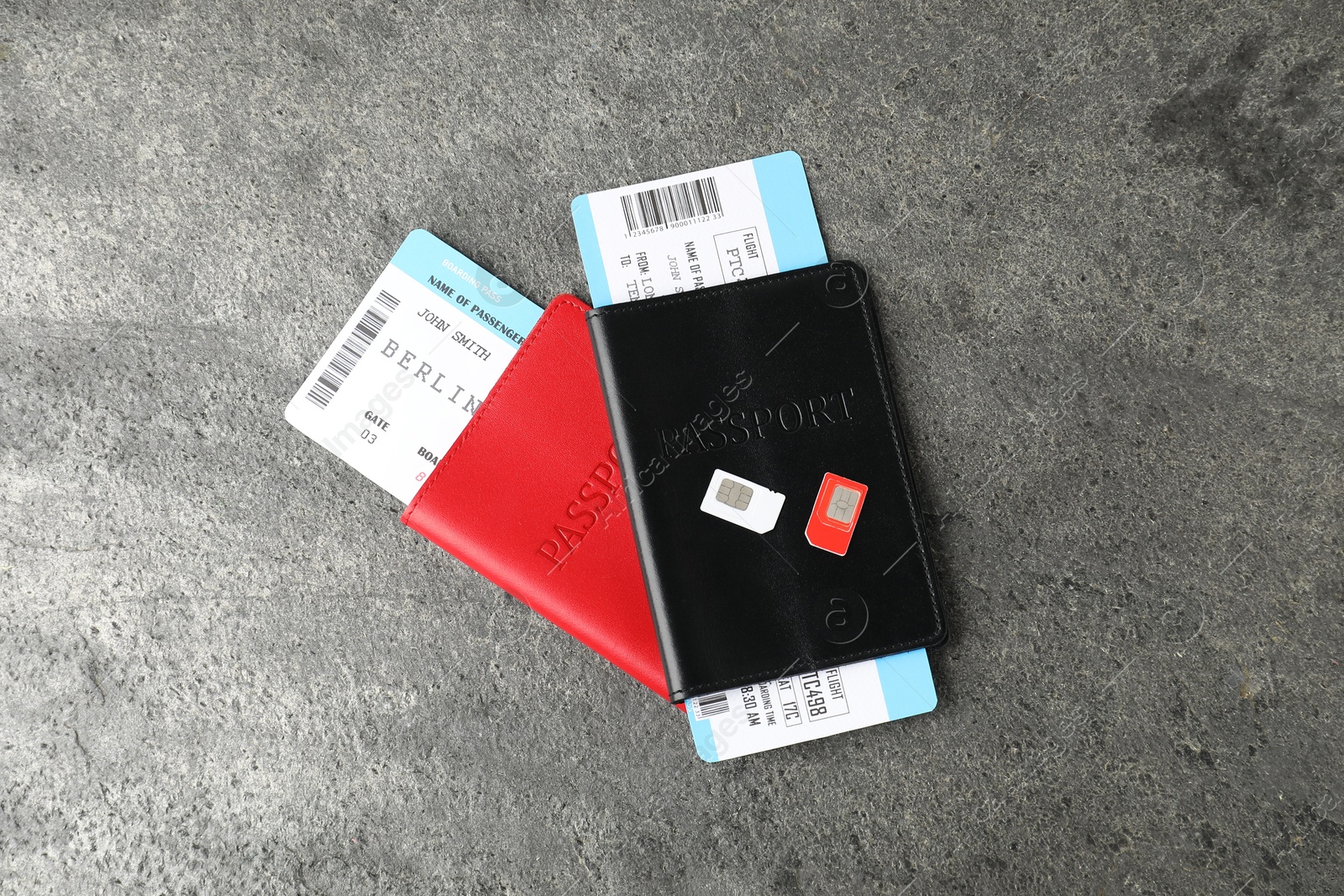 Photo of Passports with tickets and SIM cards on grey textured table, flat lay