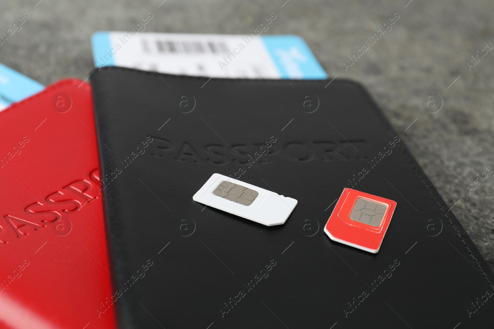 Photo of Passports with tickets and SIM cards on grey table, closeup