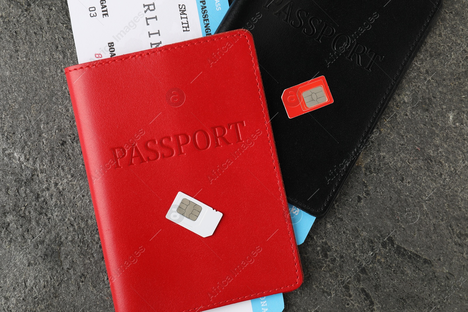 Photo of Passports with tickets and SIM cards on grey textured table, flat lay