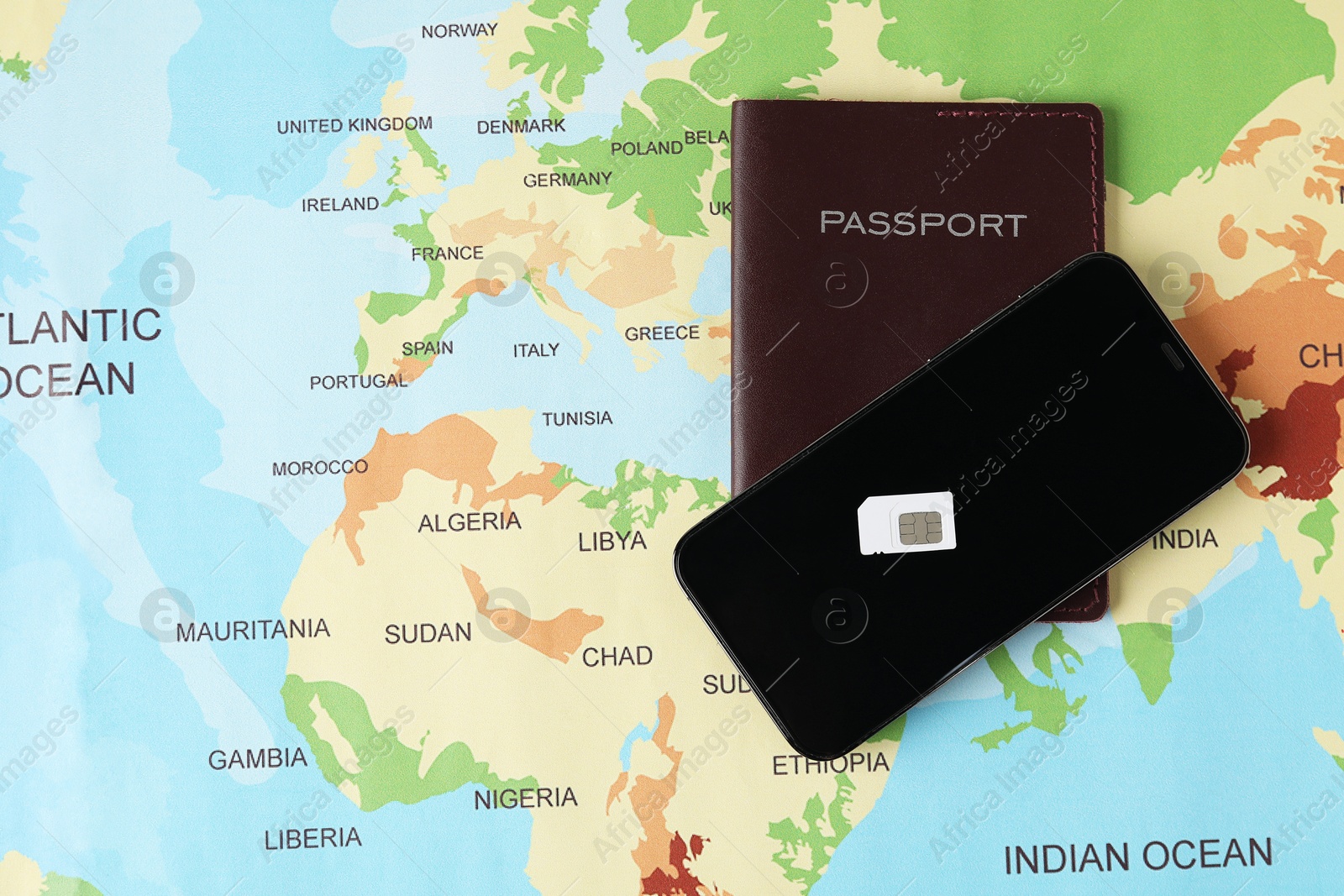 Photo of SIM card, smartphone and passport on world map, flat lay