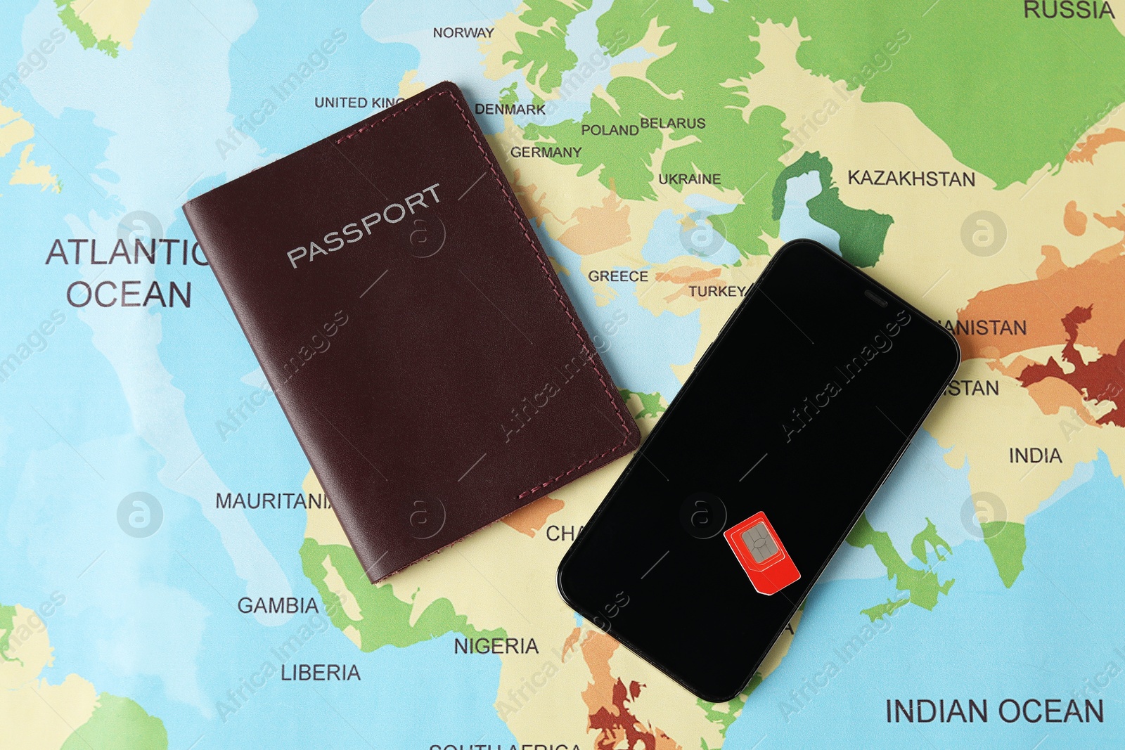 Photo of SIM card, smartphone and passport on world map, flat lay