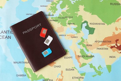 SIM cards and passport on world map, flat lay