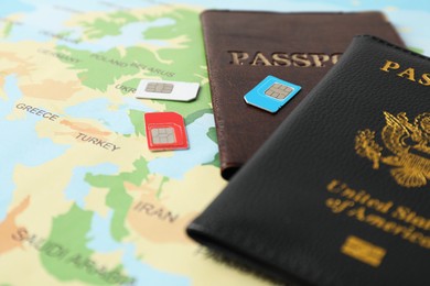 SIM cards and passports on world map, closeup