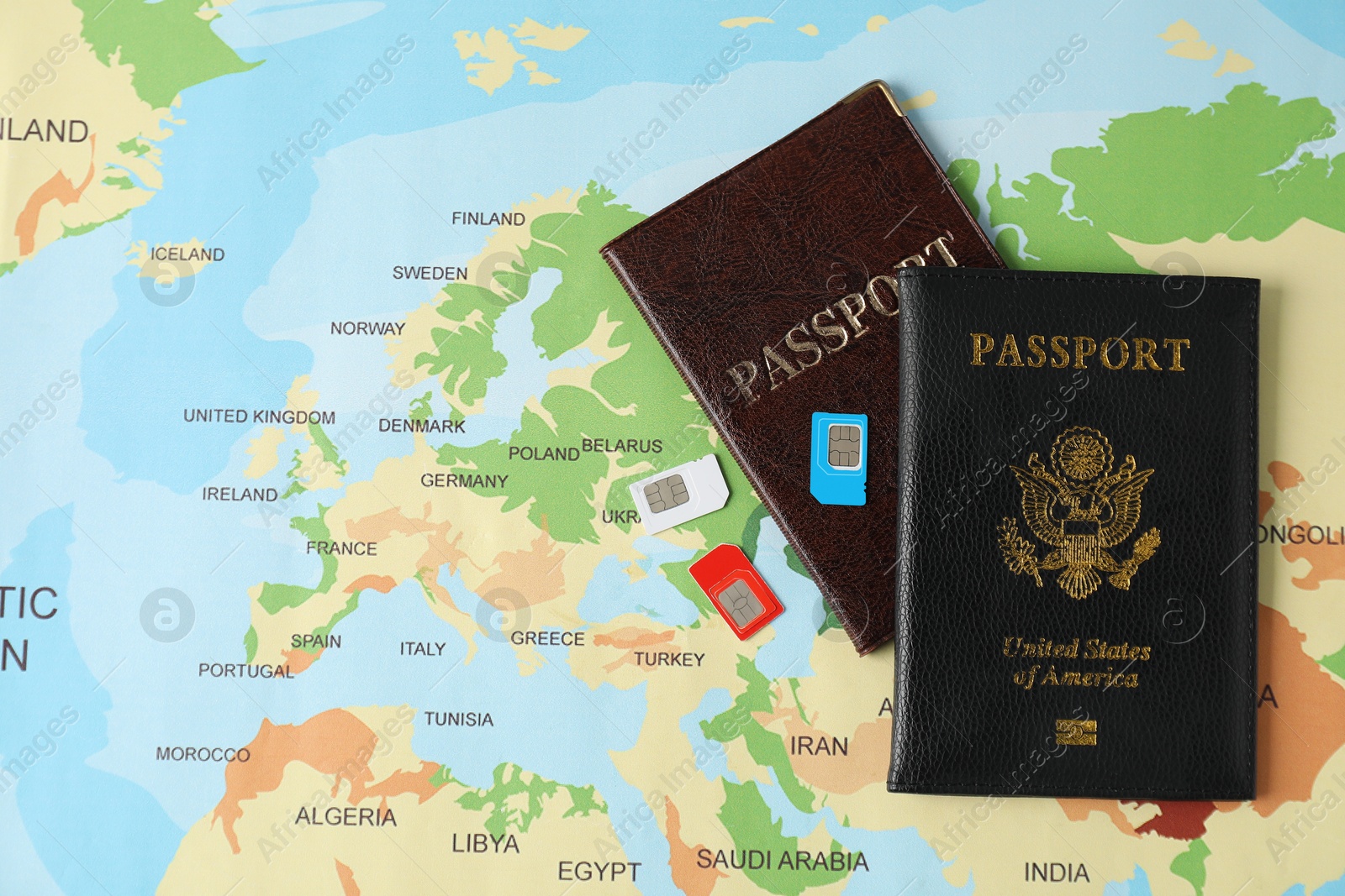 Photo of SIM cards and passports on world map, flat lay