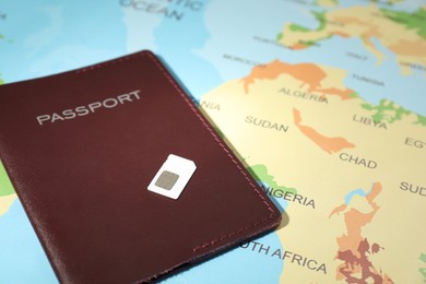 Photo of Modern SIM card and passport on world map, closeup