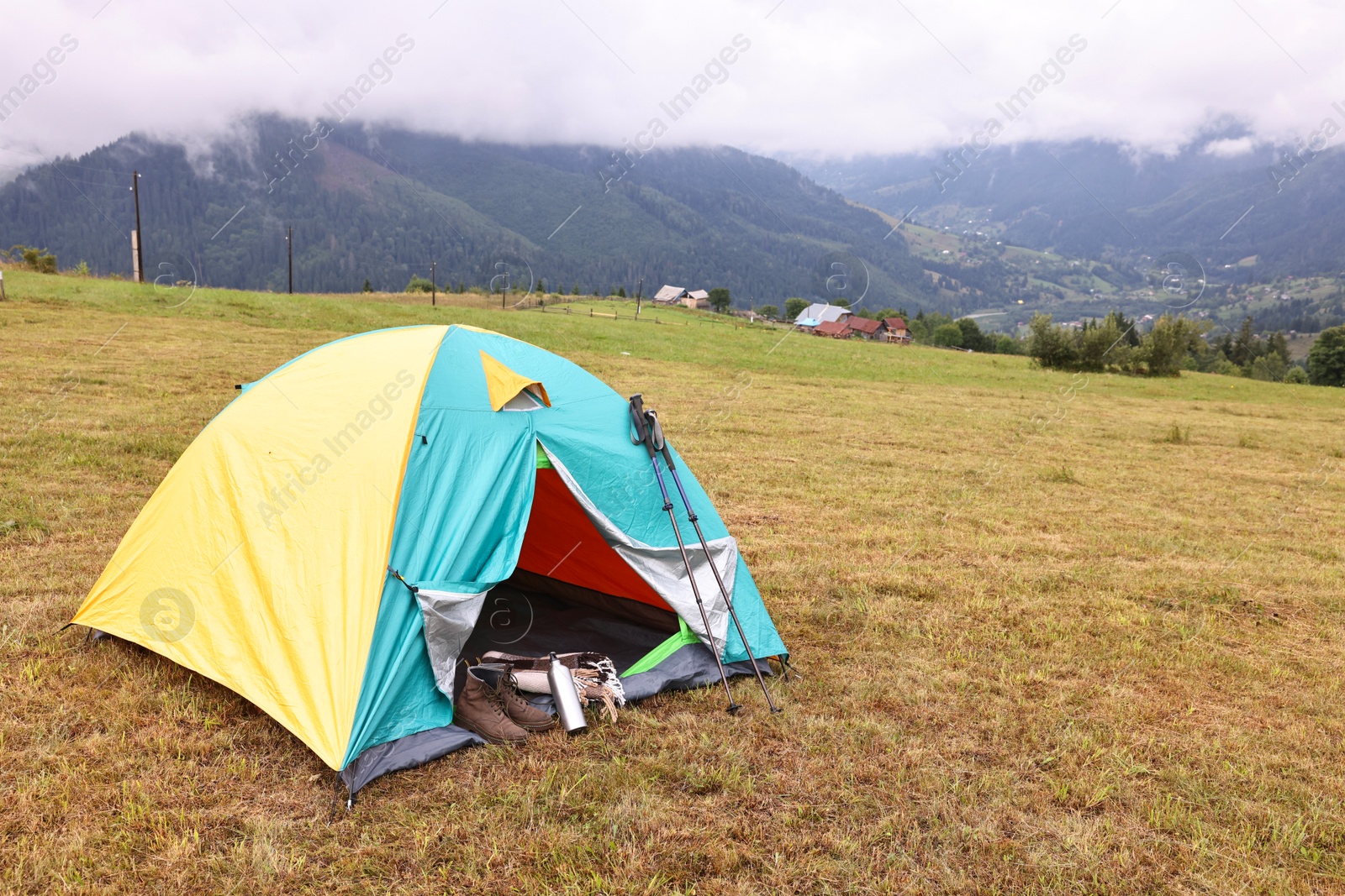 Photo of Camping tent and tourist stuff on grass in mountains, space for text