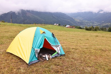 Photo of Camping tent and tourist stuff on grass in mountains, space for text