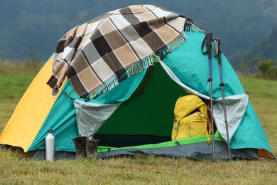 Photo of Camping tent and tourist stuff on green grass in mountains