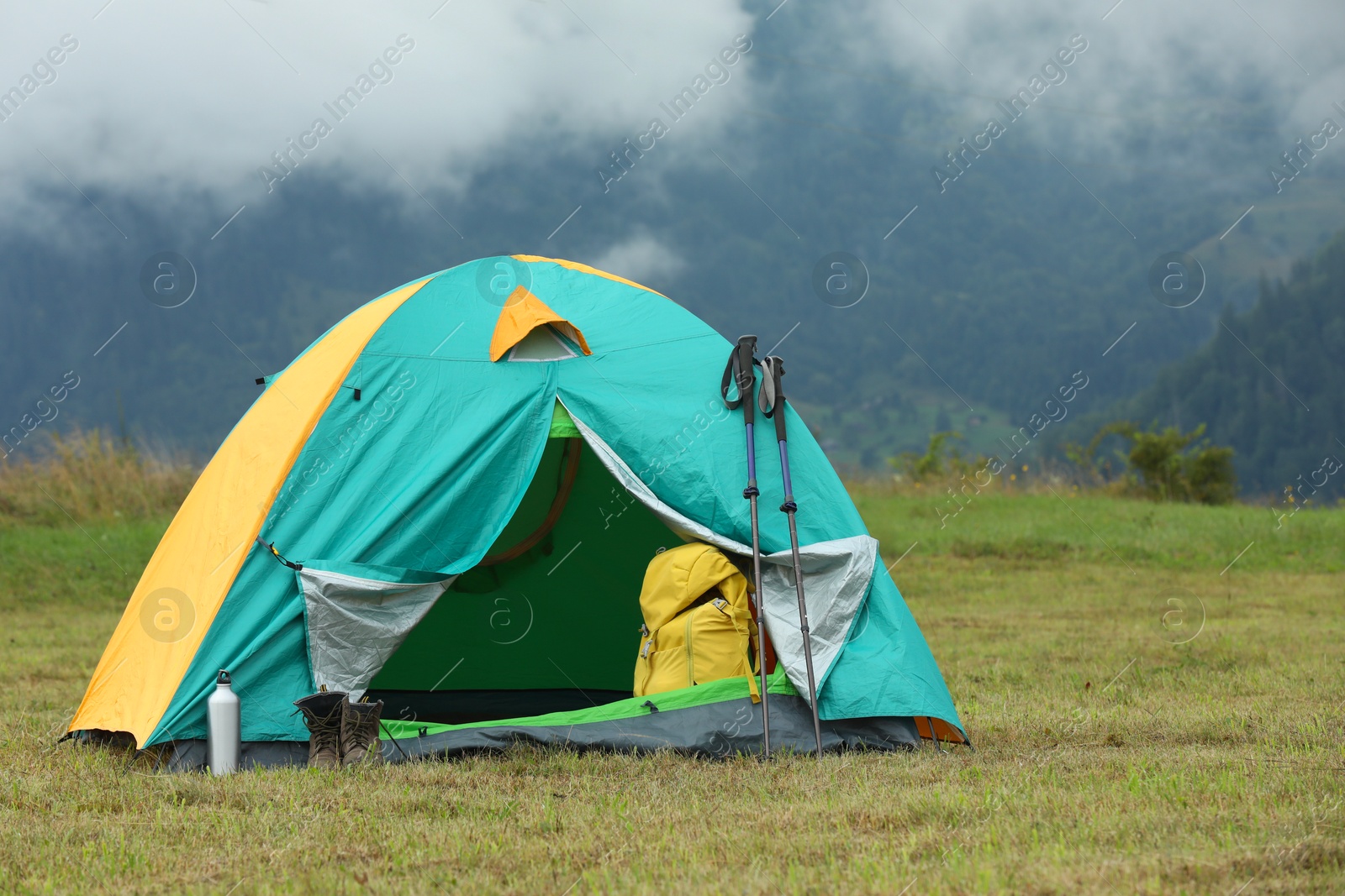 Photo of Camping tent and tourist stuff on green grass in mountains