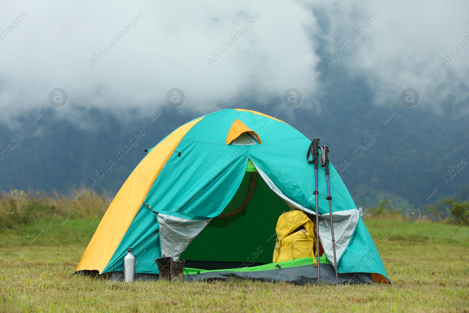 Photo of Camping tent and tourist stuff on green grass in mountains