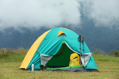 Photo of Camping tent and tourist stuff on green grass in mountains